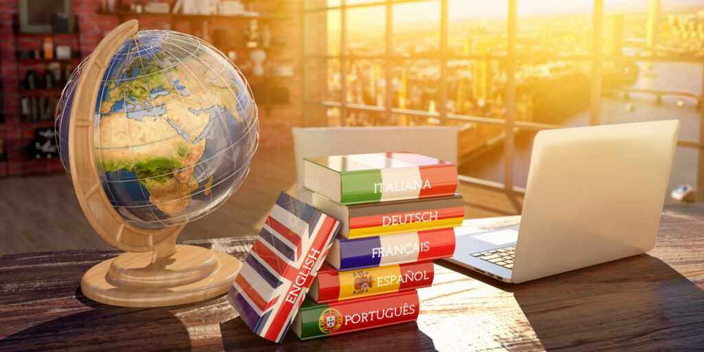 table with globe, laptop and translation dictionaries